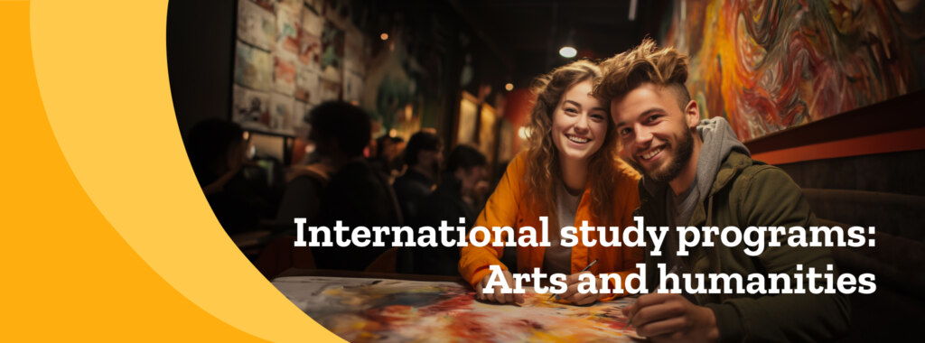 A female and male student in an arts and humanities international study program pause from drawing and smile, with art around them.