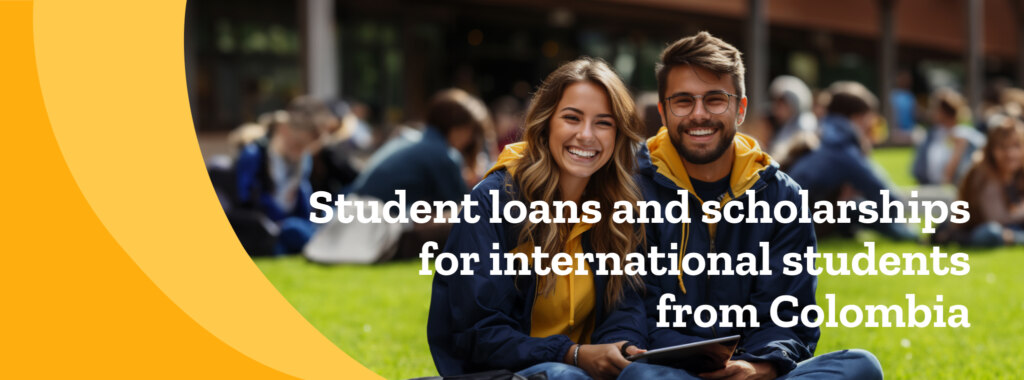 A female and male international student with yellow hoodies and blue jackets sit outside, smiling at the camera.