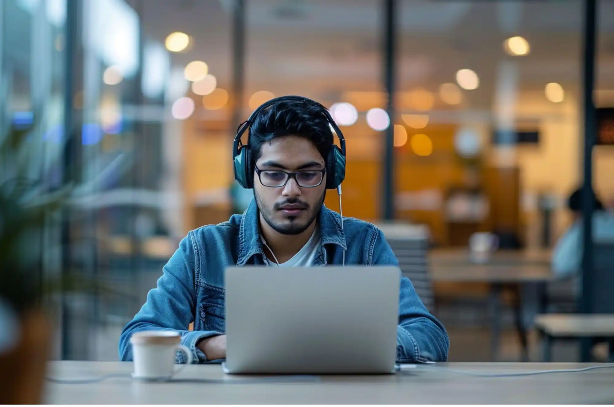 A Nepali student sits at a desk in a modern office workspace