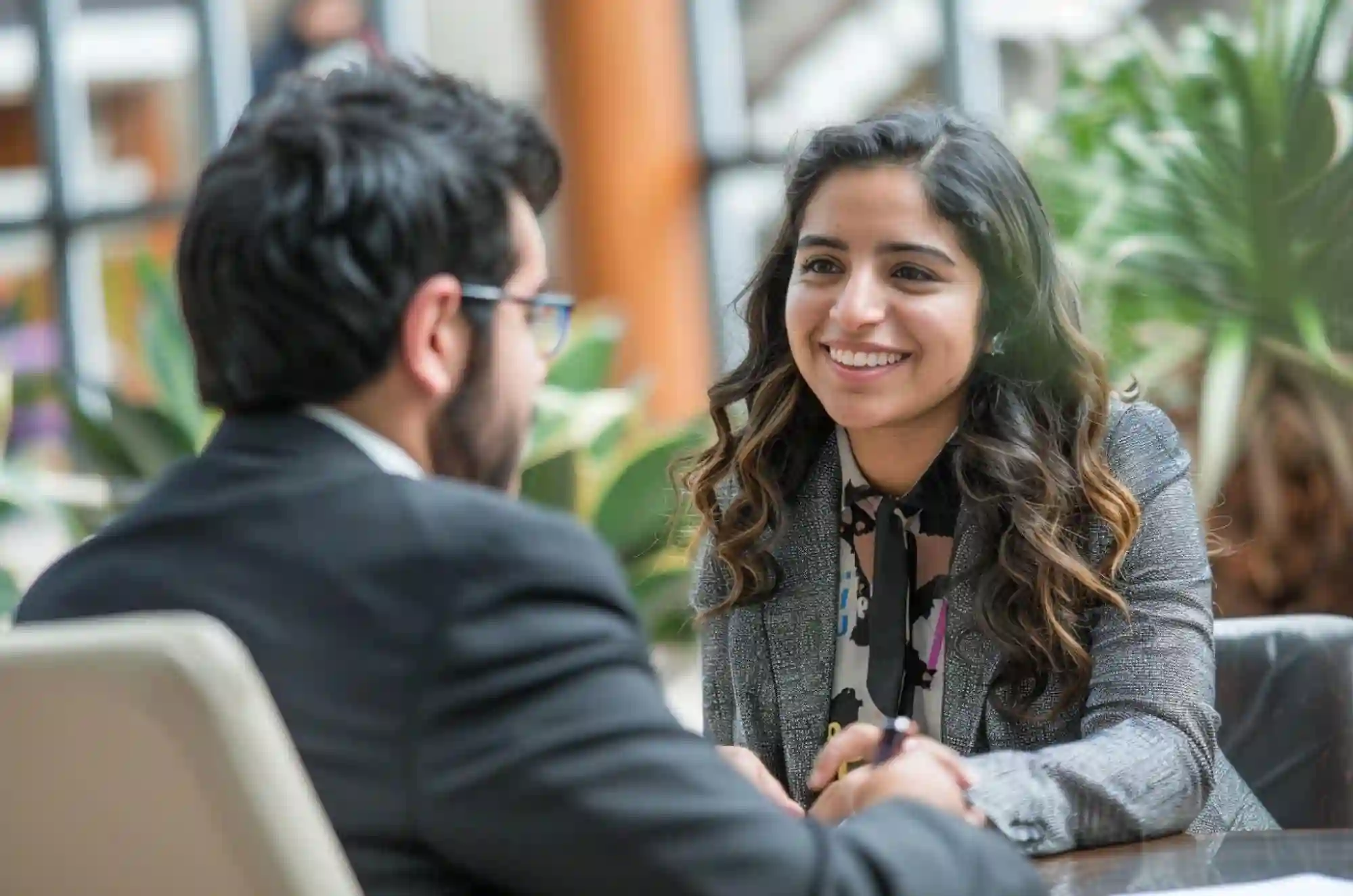 International student dressed in formals, speaking to a recruiter in a career fair.