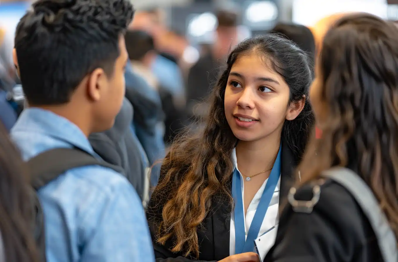 A group of students, including one from Colombia, talk with recruiters at a university career fair.