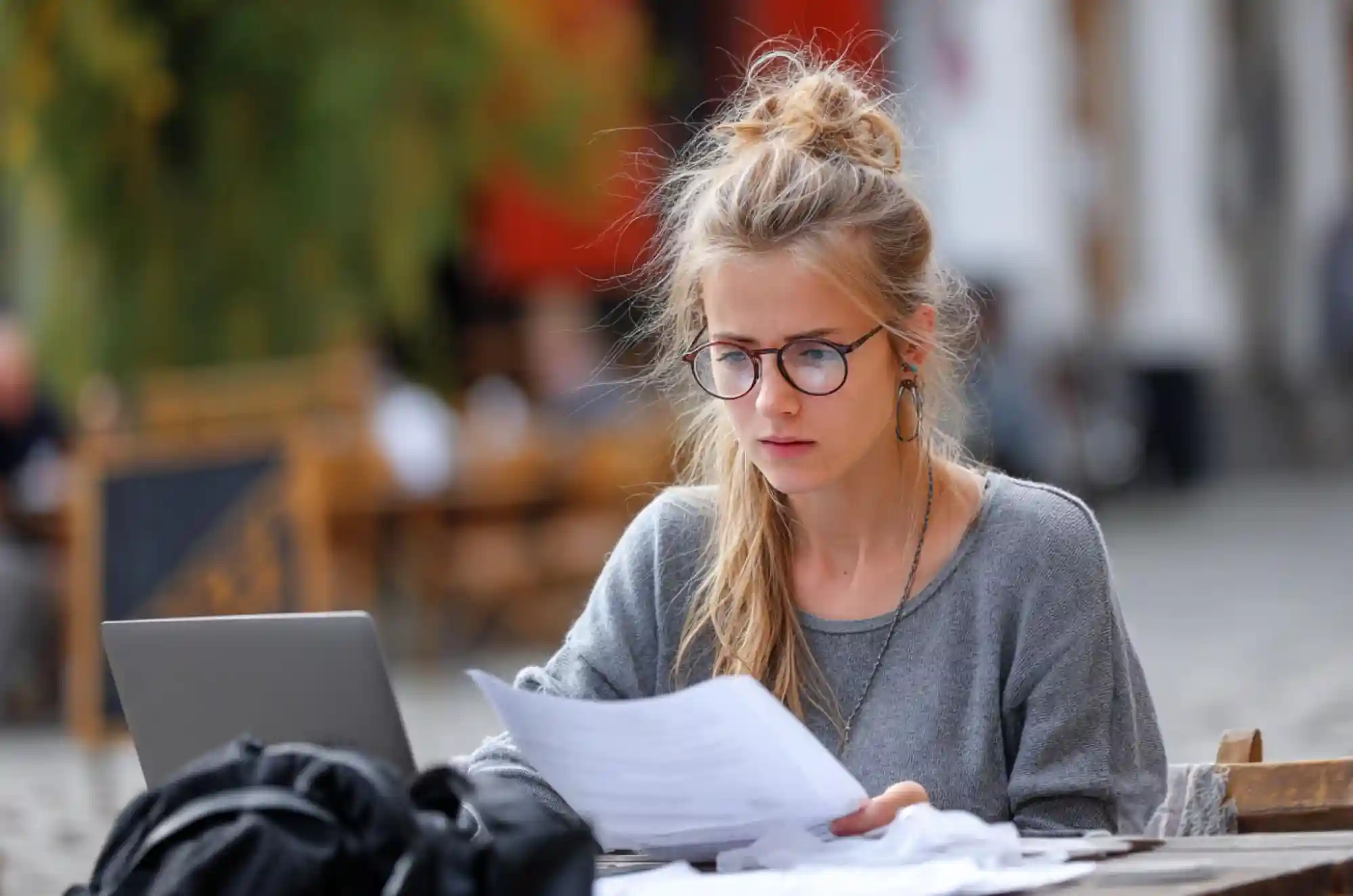 International student in a cozy coffee shop reviewing the visa application process on a laptop, with a backpack.