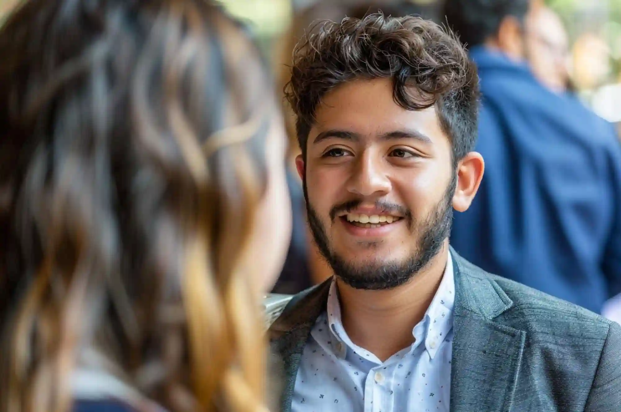 A Colombian graduate student attending a university job fair or networking event speaks to a recruiter
