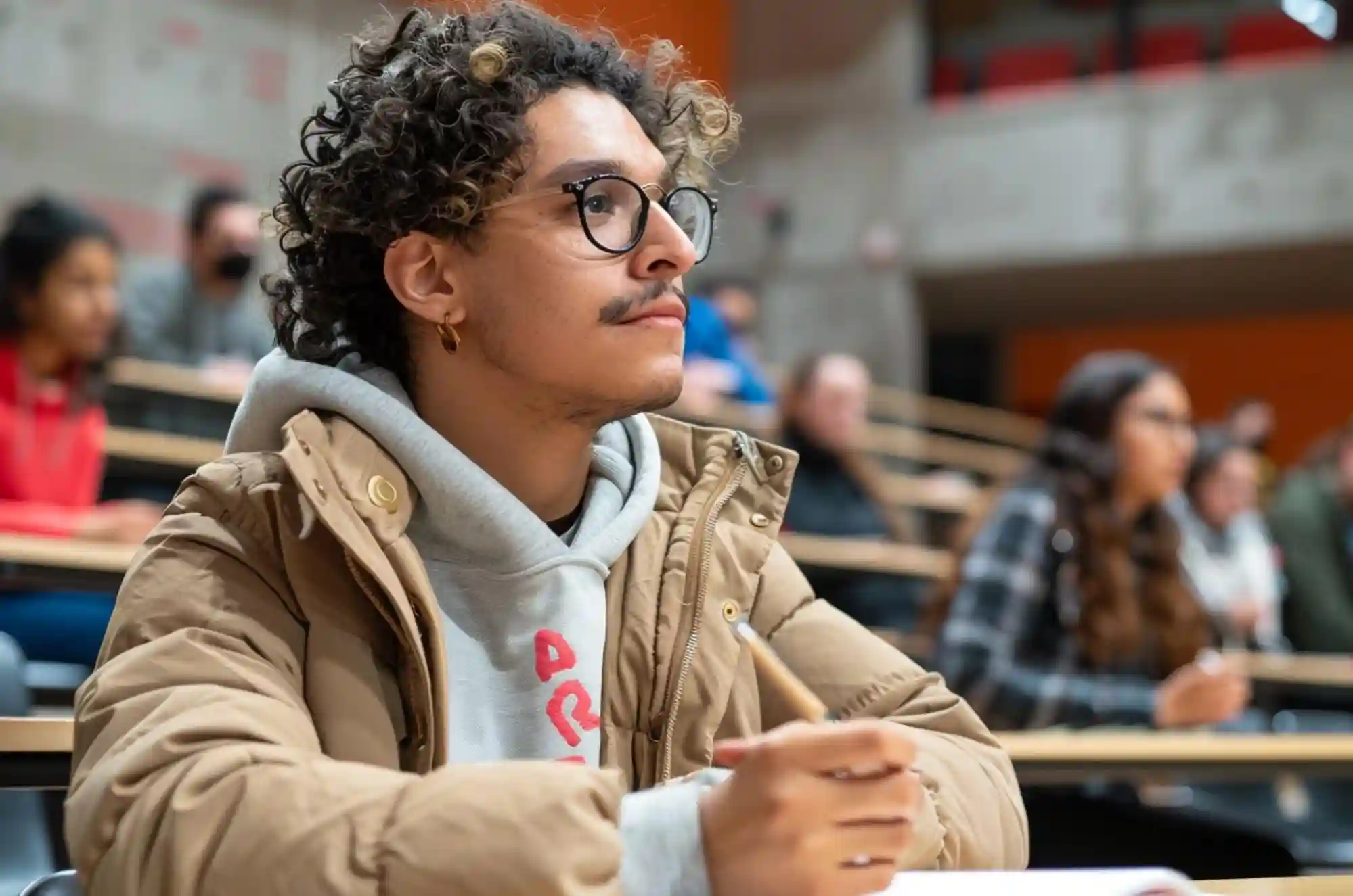 A Columbian student wearing a jacket, takes notes in a lecture hall.