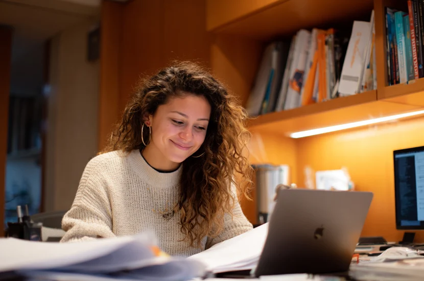 A Colombian student on an F-1 visa reviewing documents on a laptop in a cozy apartment