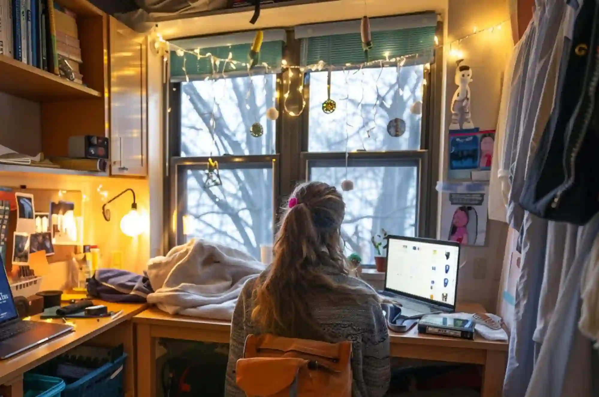 A dorm room scene shows a student sitting at her desk. On the wall are posters and a calendar marked with university events.