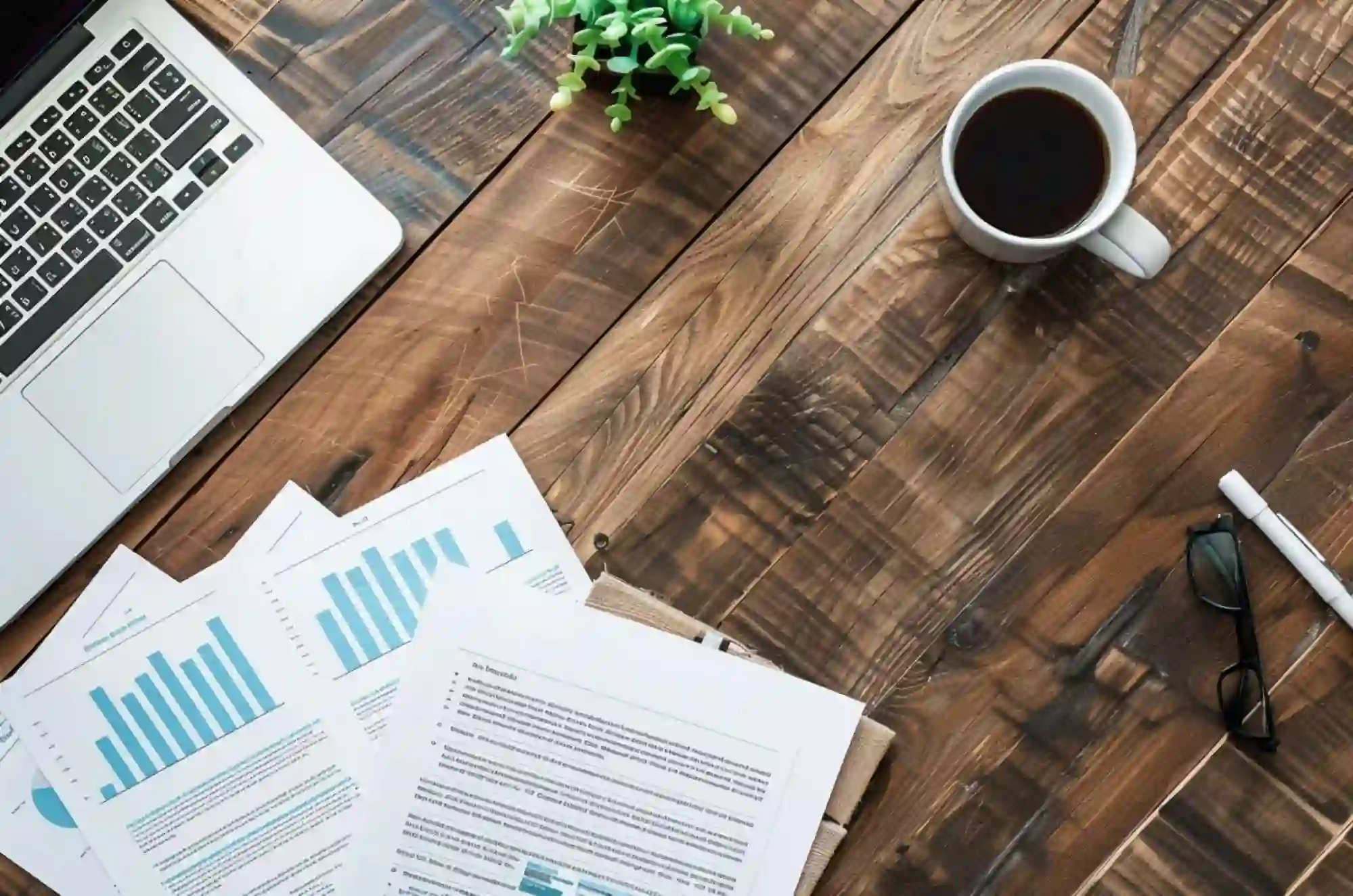 A flat lay photo shows a desk with a laptop and some papers.