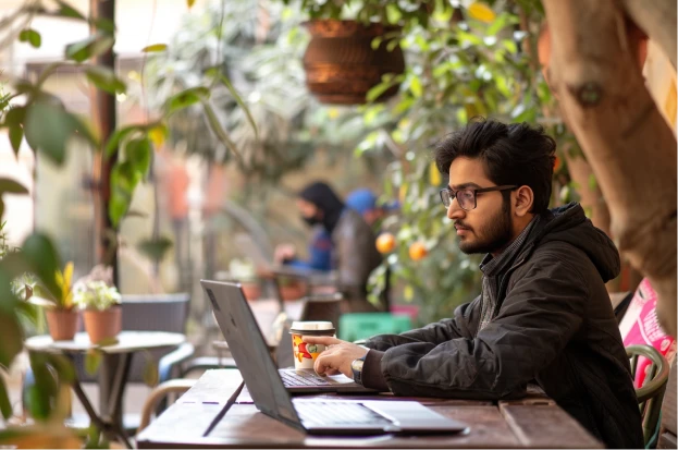 An Indian student in Mumbai works on a U.S. university application at a modern co-working space.