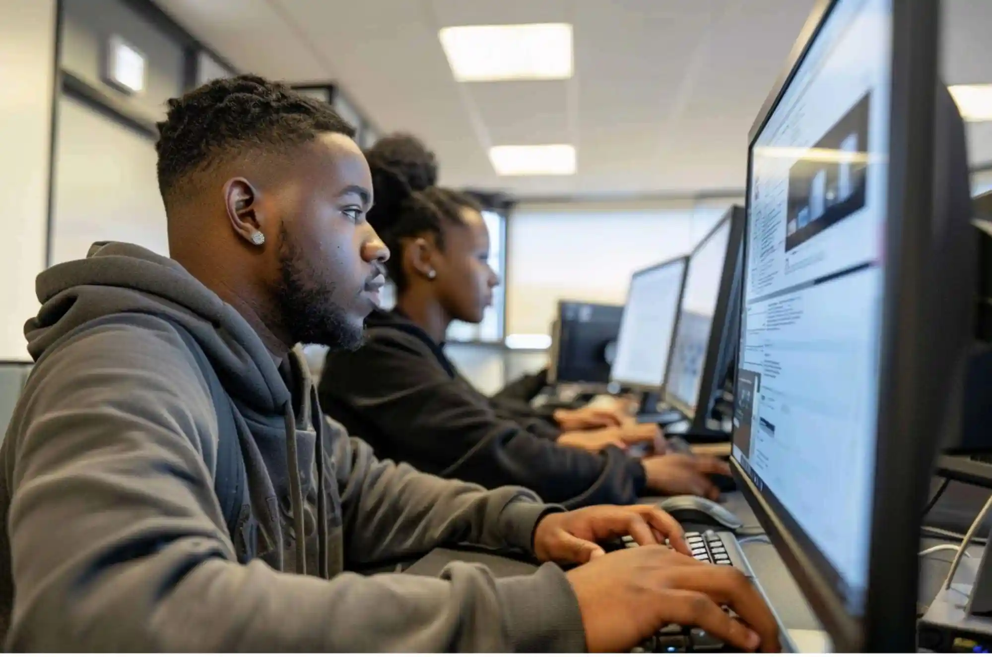 Two students sit side by side in a campus computer lab reviewing tax software on their screens.