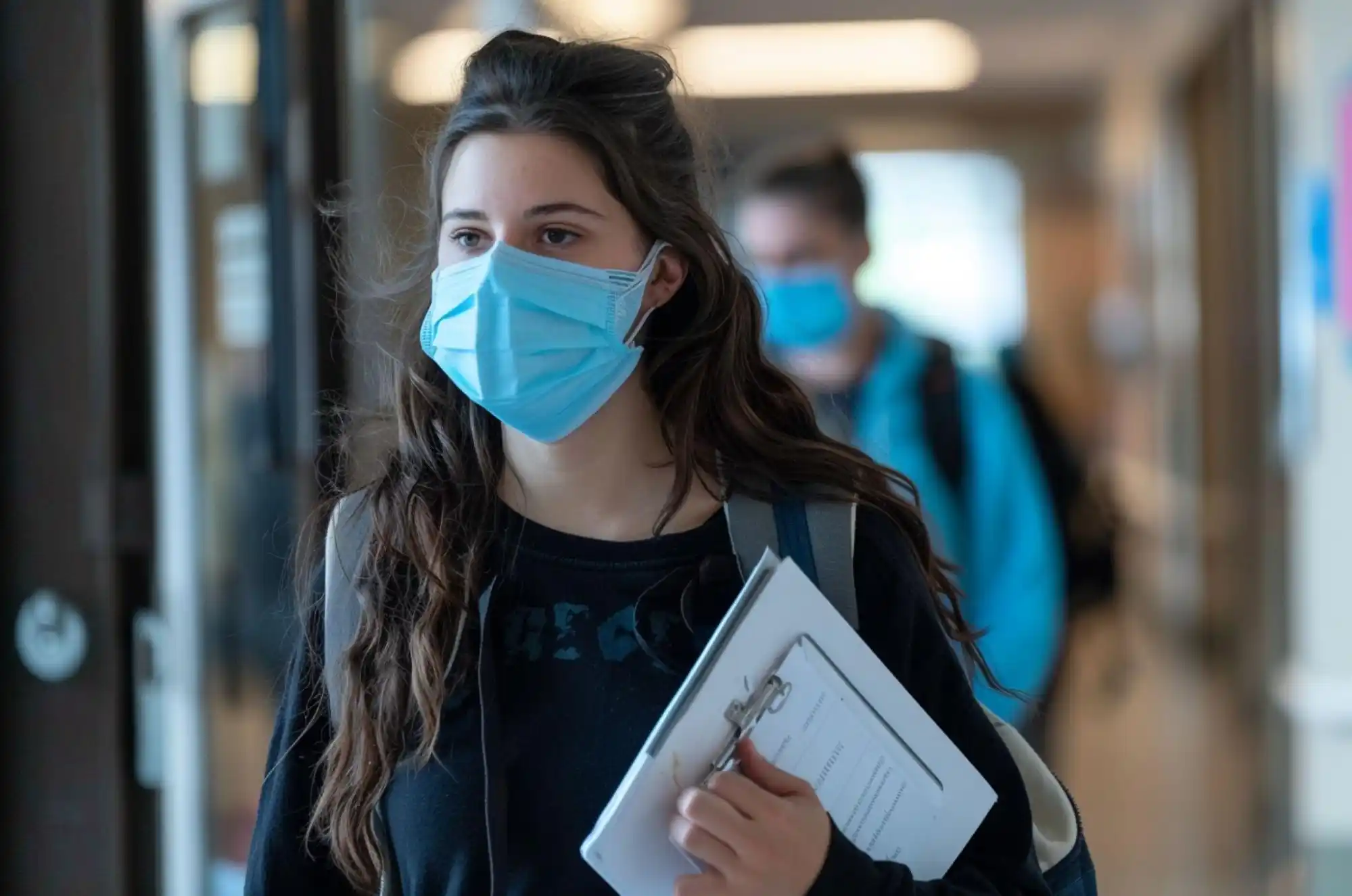 A student walks out of a university clinic holding a folder labeled.