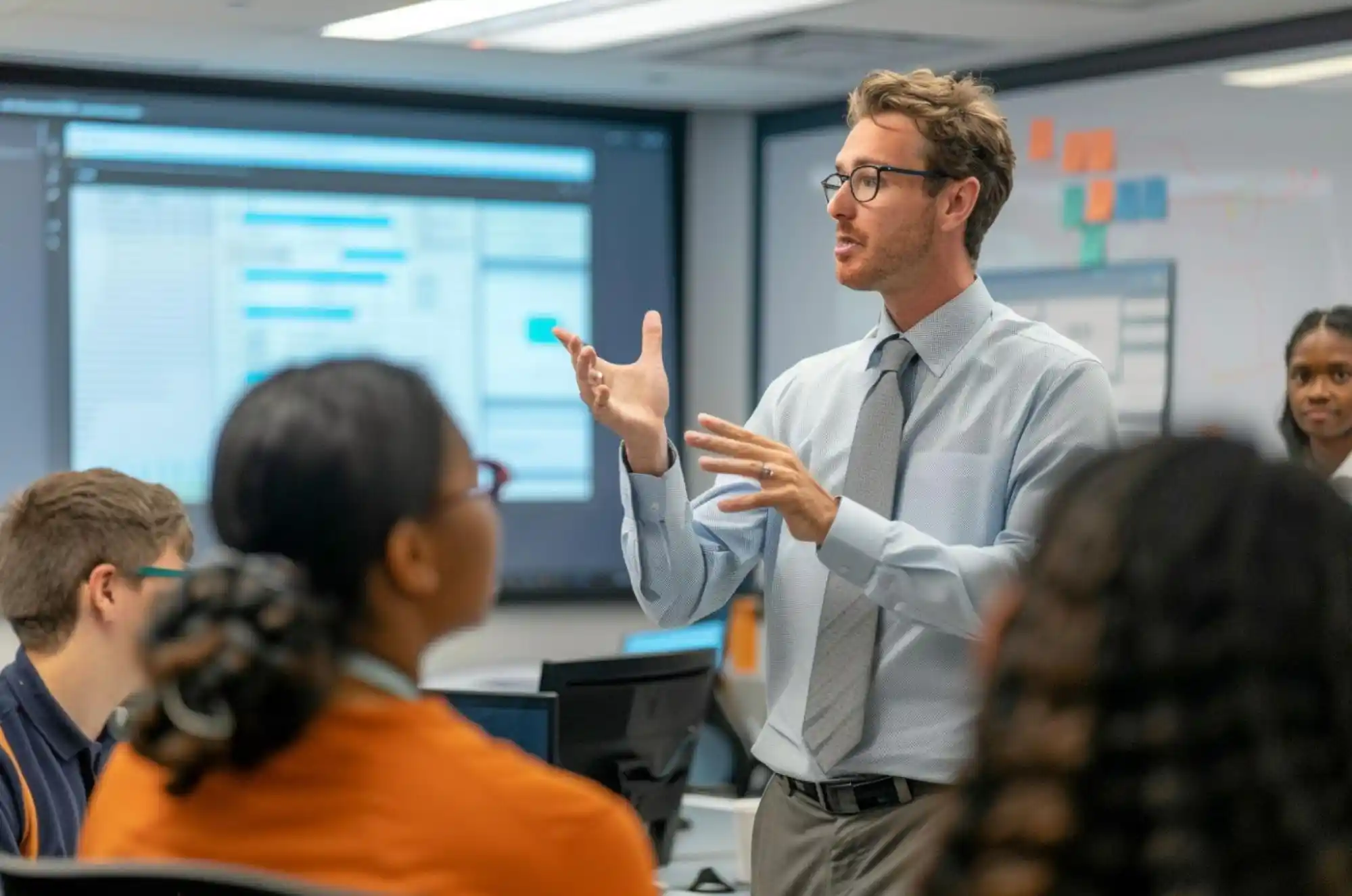 U.S. tech office during a student open house, a diverse group of masters students listens to a product manager