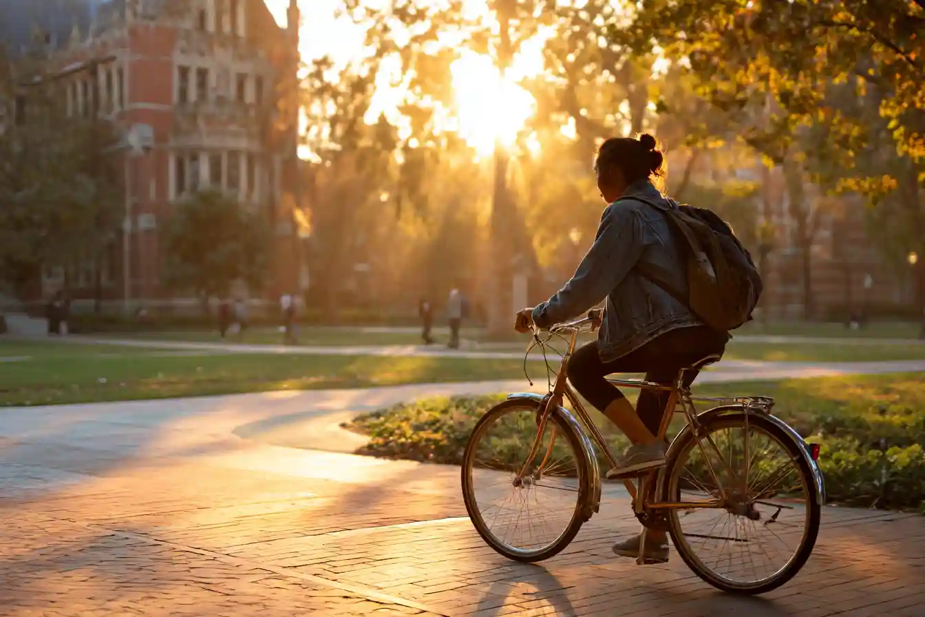 Insert Image alt text hereInternational postgraduate student riding a bike through a quiet campus in the early morning light, showing independence and focus on academic life abroad.