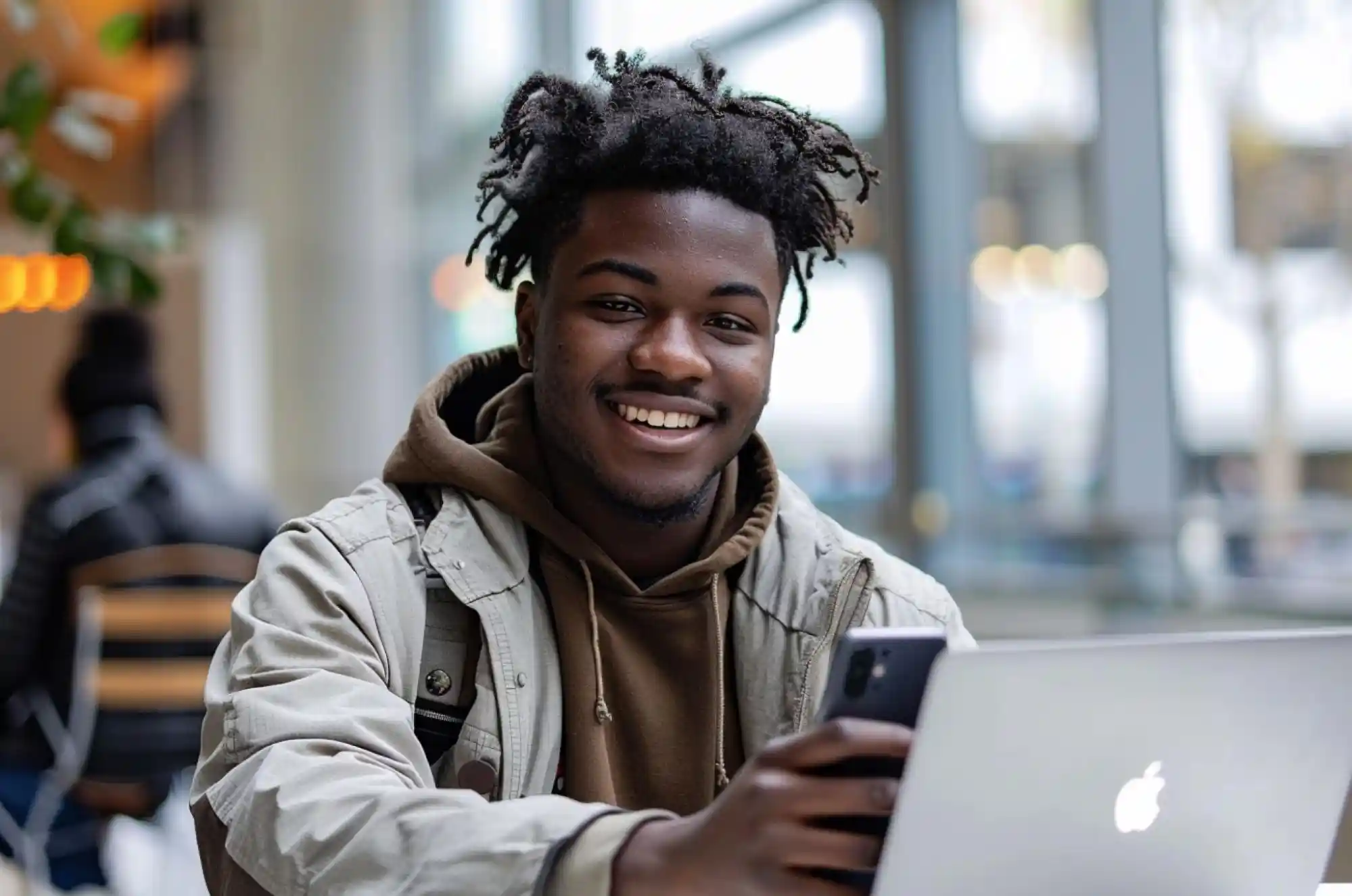 A student smiles while checking their phone on a study table, capturing the relief and excitement of the moment